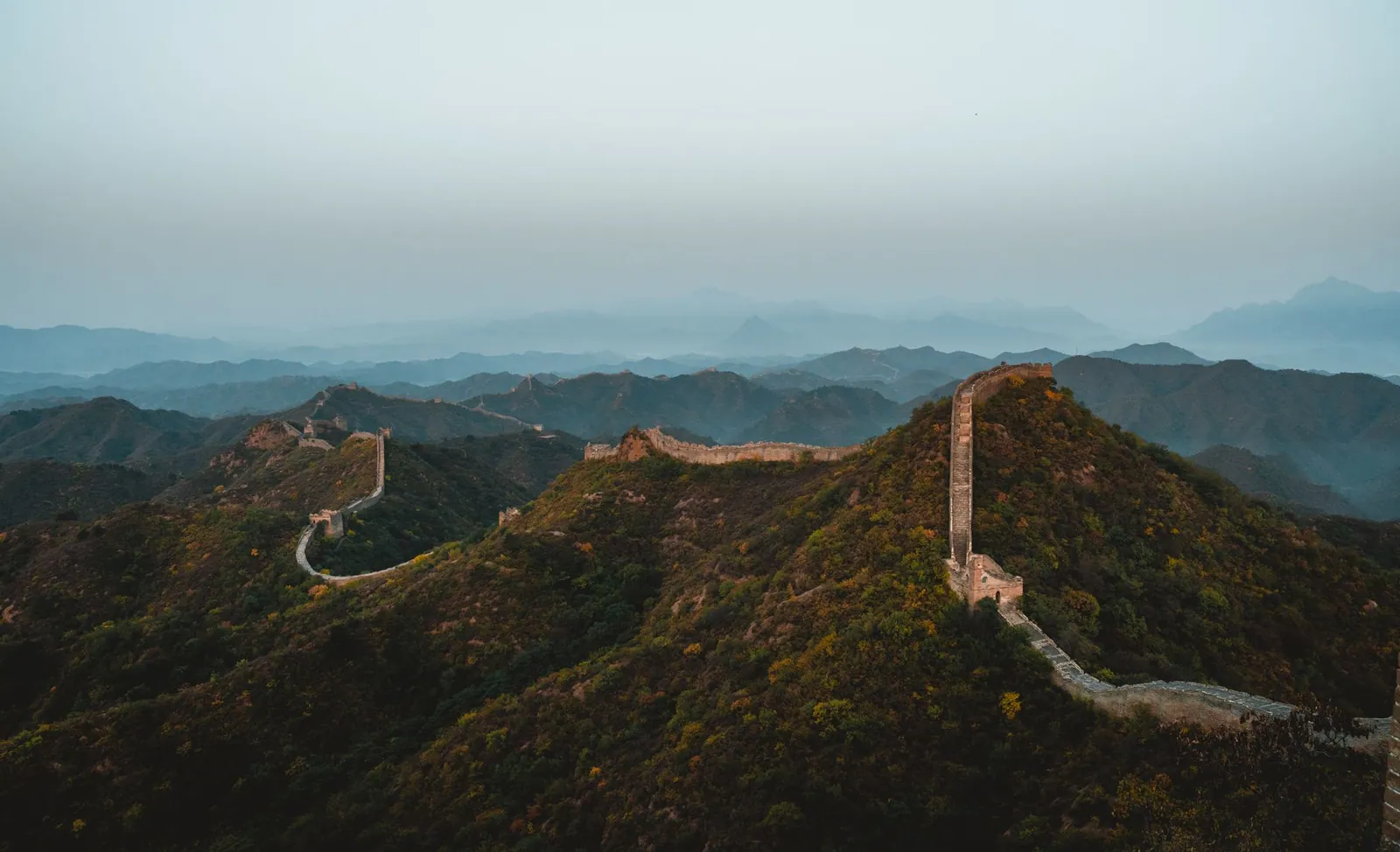 Aerial view of the Great Wall of China stretching across rugged hills at dusk
