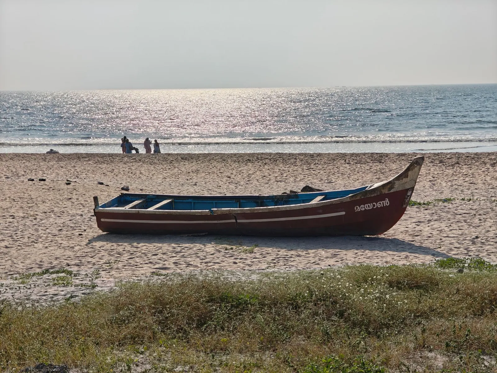A traditional boat on a sunlit beach on India's west coast