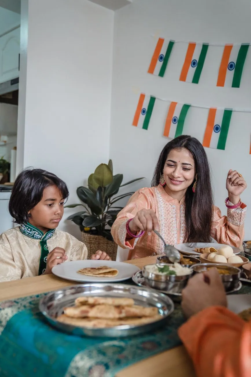 A joyful Indian family enjoying traditional food indoors with festive decor