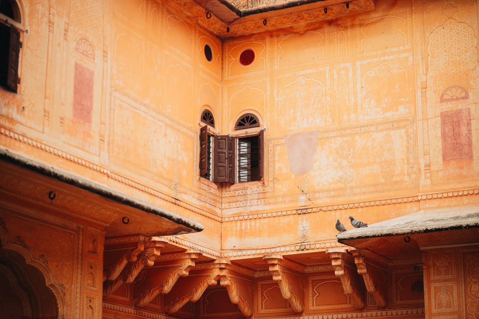 A serene view of traditional Rajasthani architecture with pigeons on a ledge in Jaipur, India
