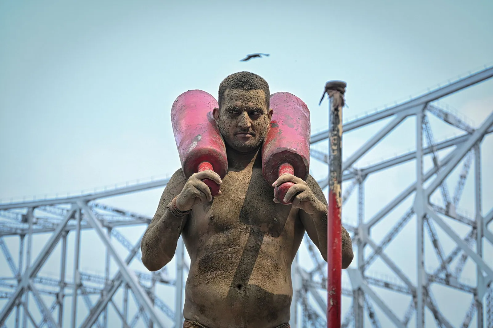 A mud-covered wrestler practises under the Howrah Bridge in Kolkata, India