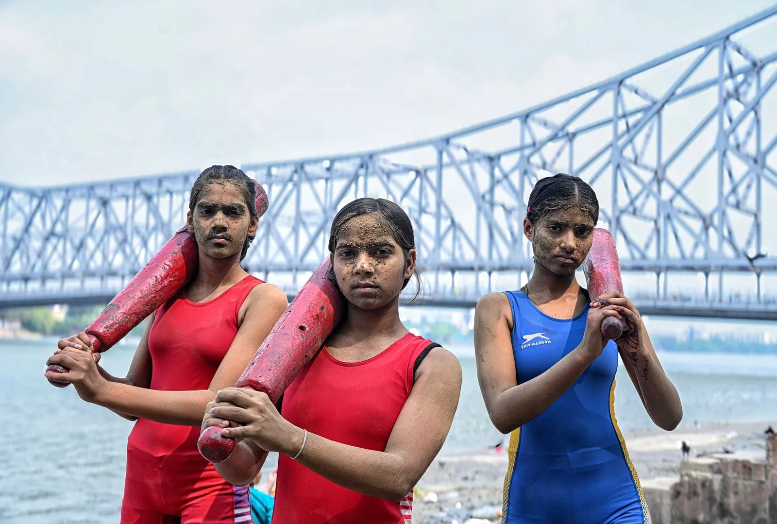 Three young athletes training with Indian clubs near the Howrah Bridge in Kolkata, India