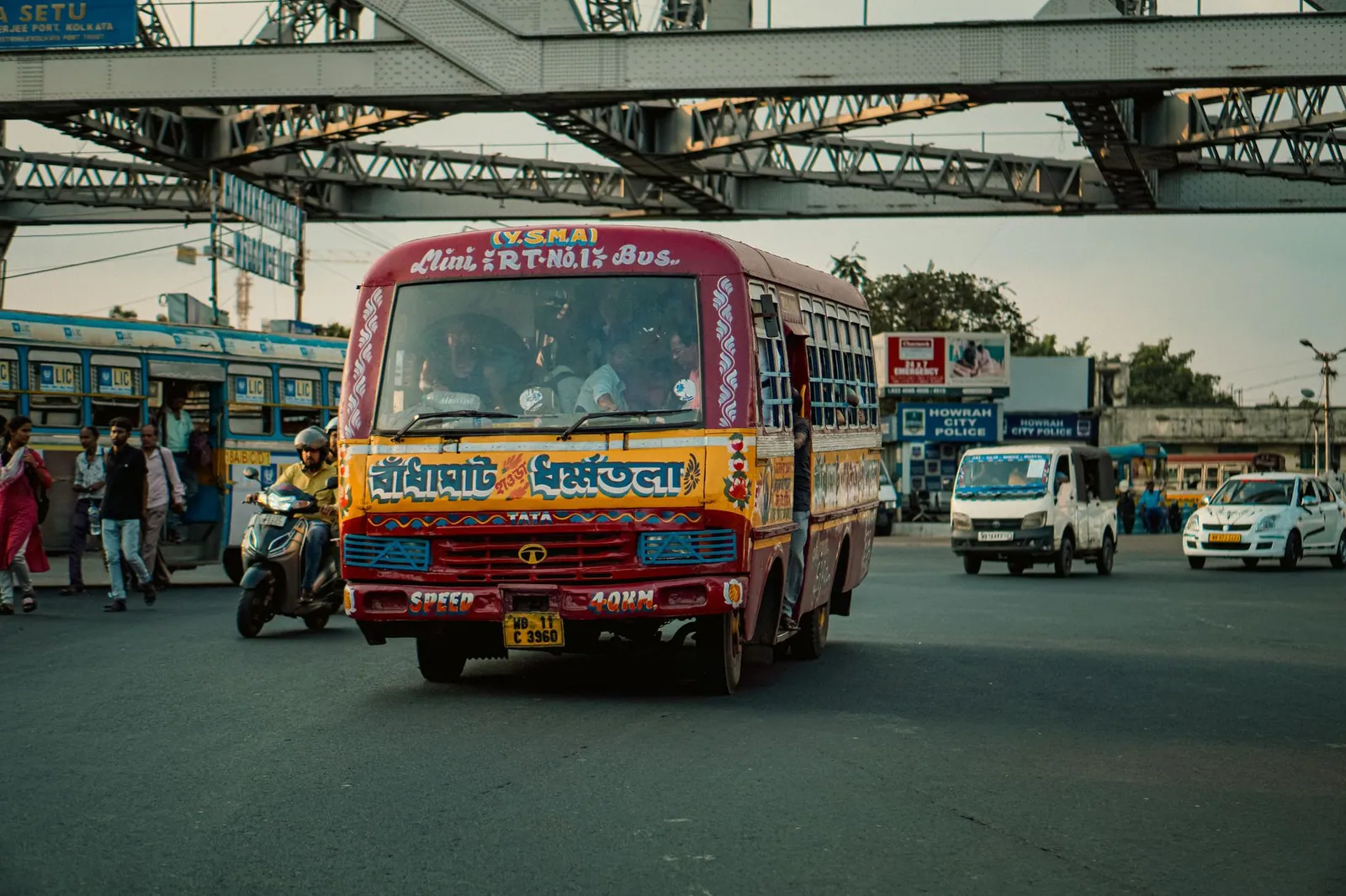 Vibrant city scene in Kolkata, India with colorful bus, vehicles, and commuters.