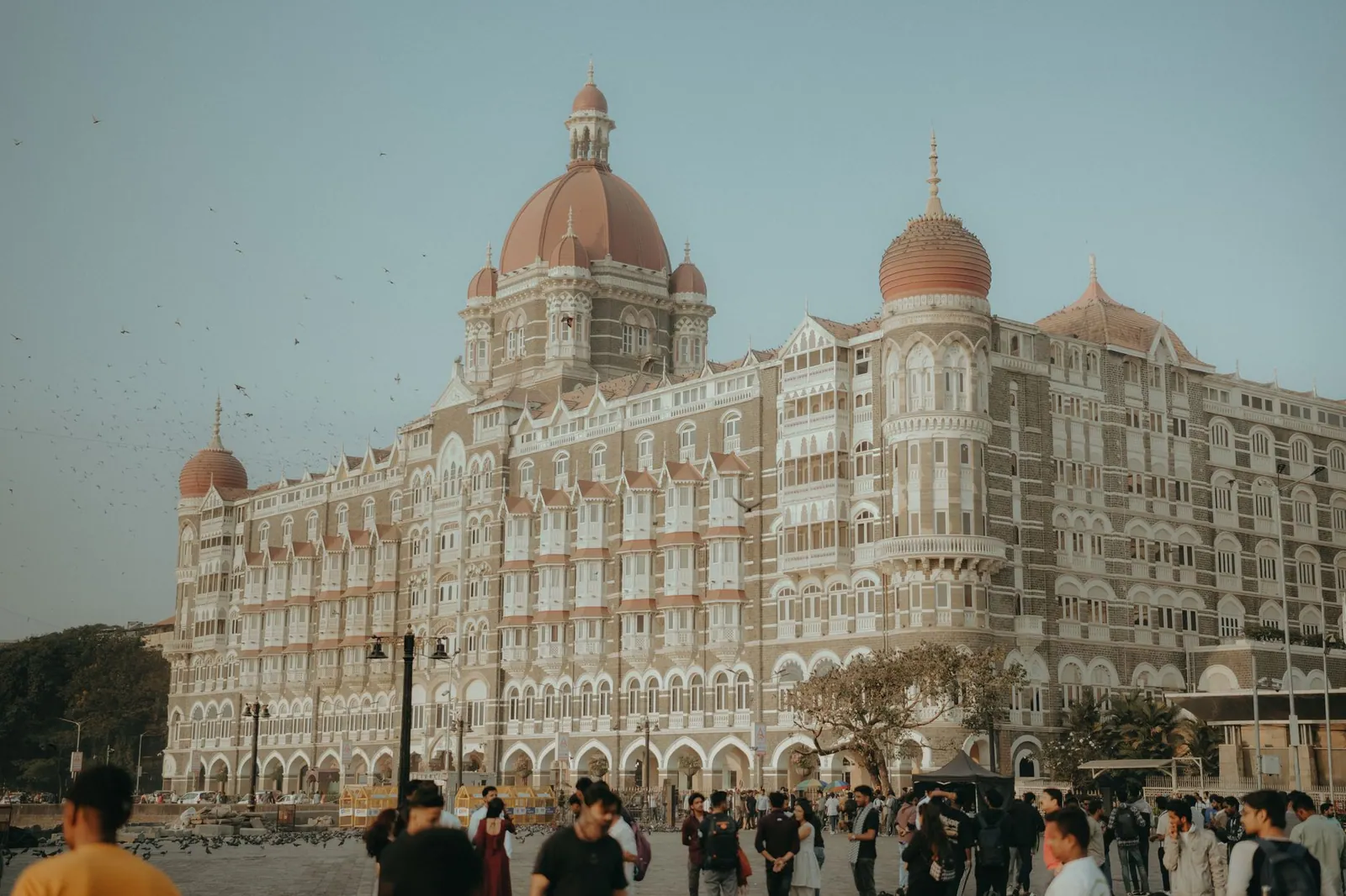 Capture of The Taj Mahal Palace Hotel in Mumbai, India with people in the foreground at twilight.
