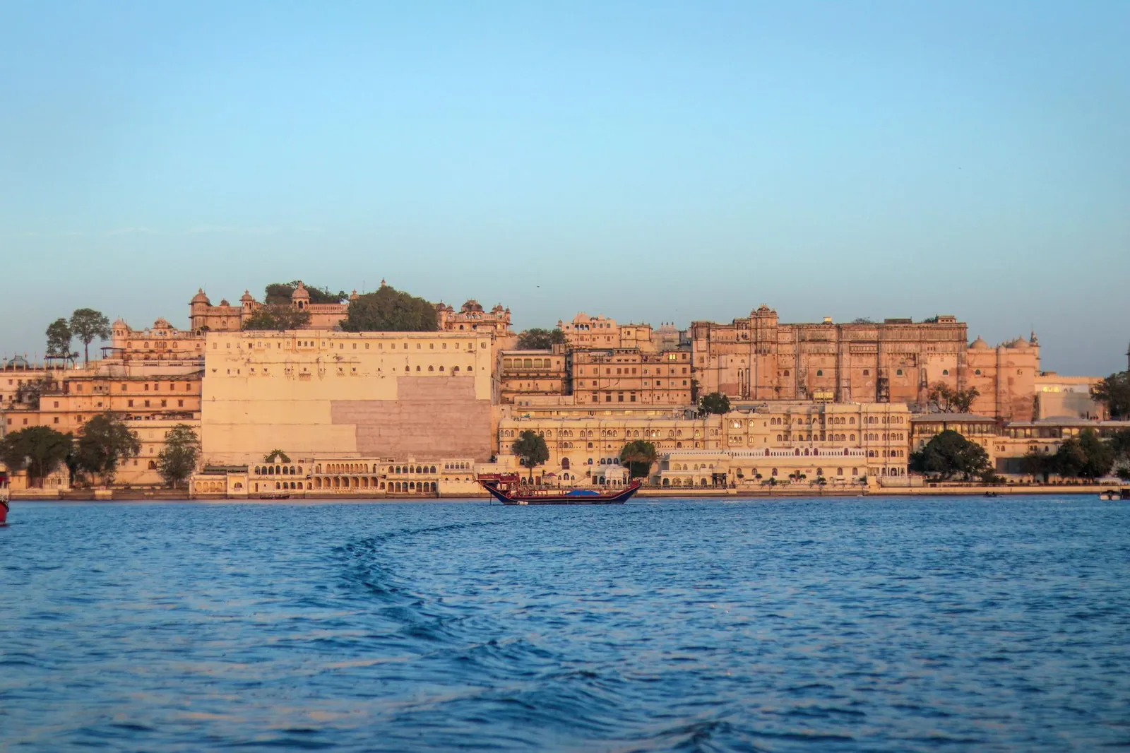 The historic Udaipur City Palace in Rajasthan, India, across Lake Pichola at sunset
