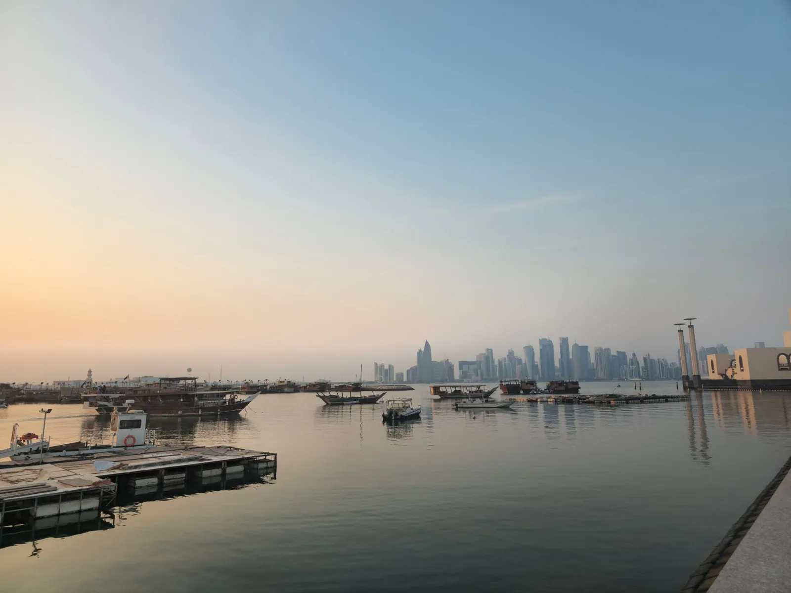 Doha skyline viewed from the waterfront with boats at sunrise, Qatar