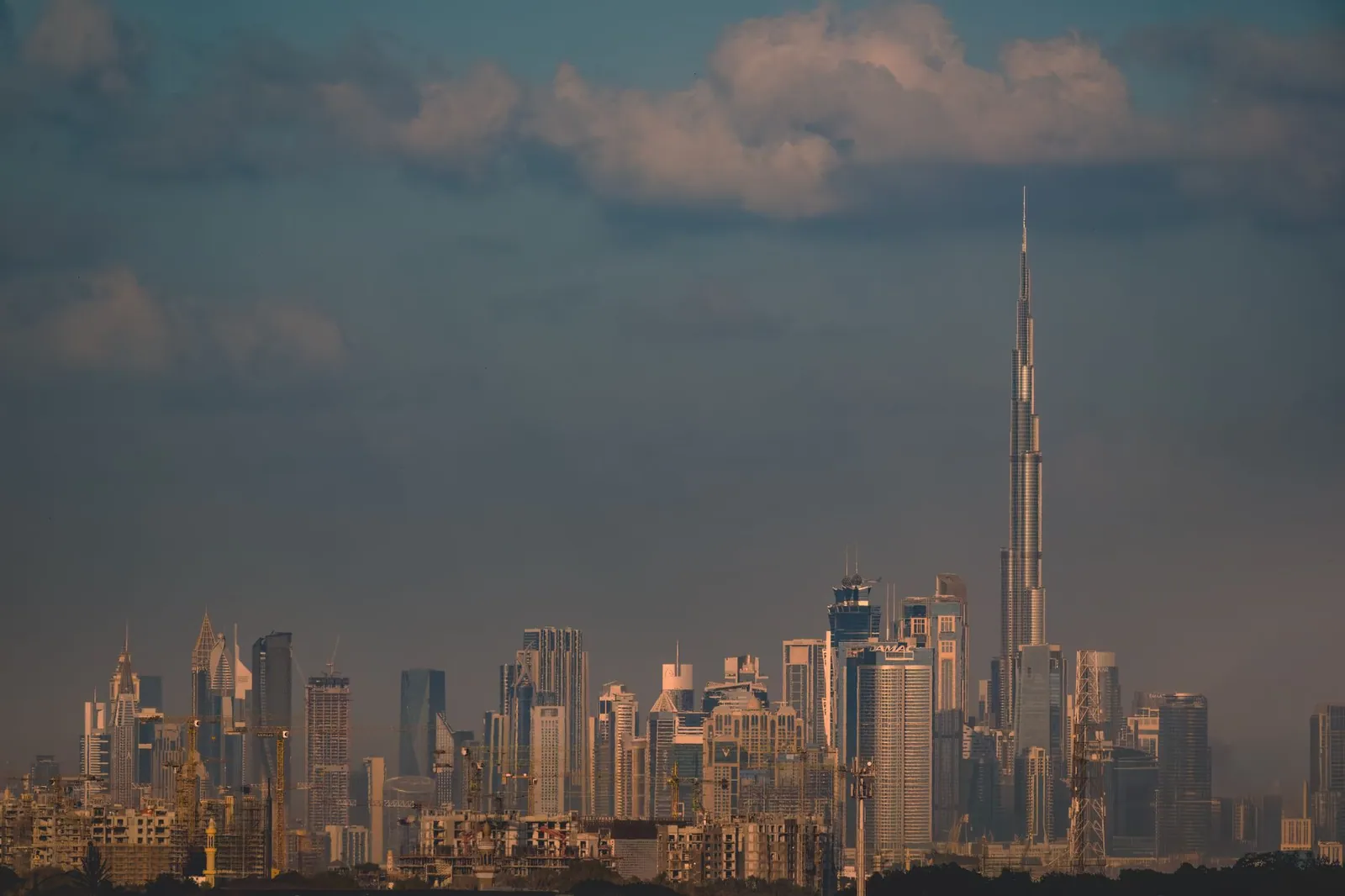 Dubai skyline with the Burj Khalifa at dusk under a cloudy sky