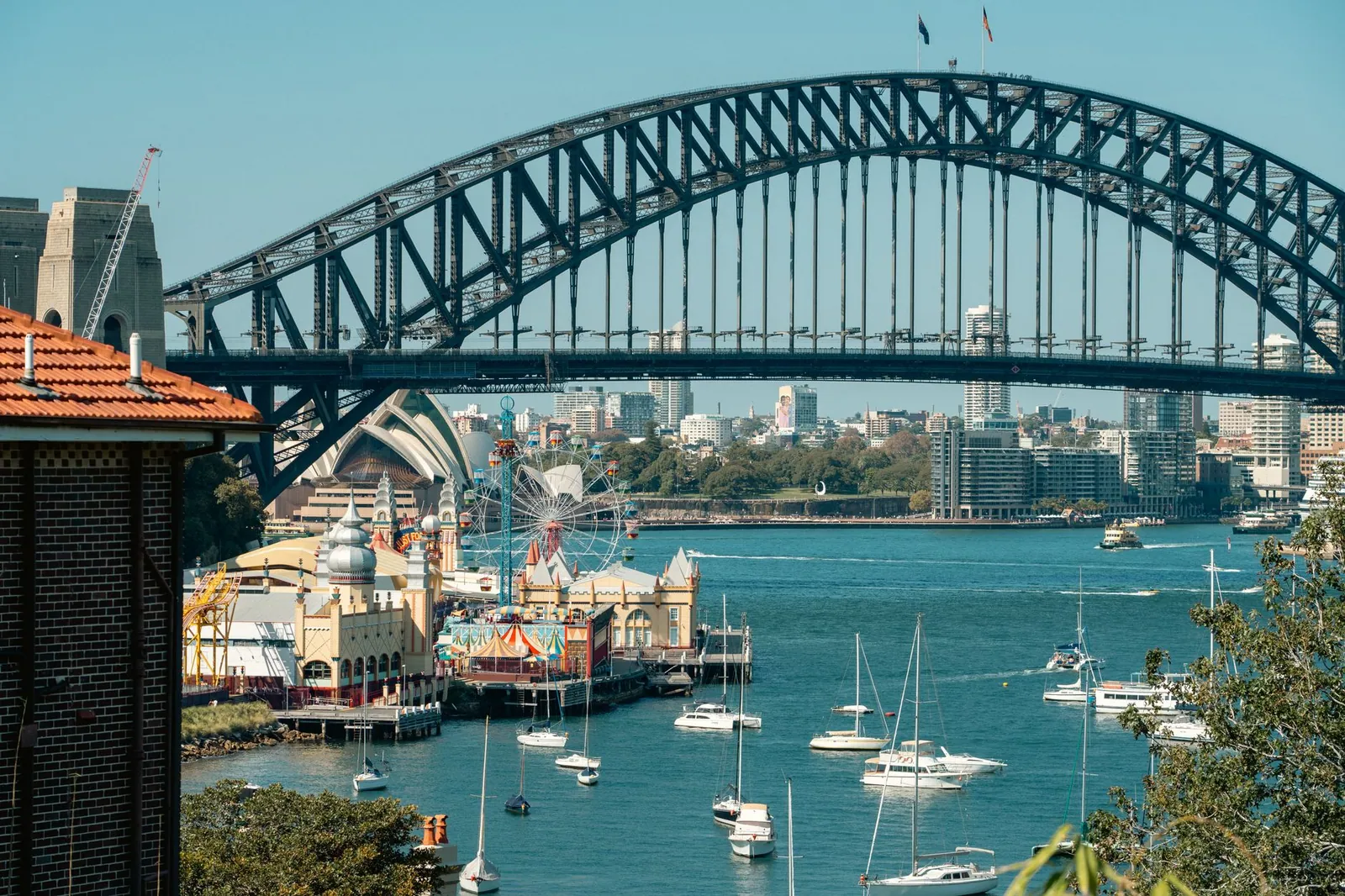 A vibrant view of Sydney Harbour Bridge with Luna Park and sailboats highlighting the iconic skyline