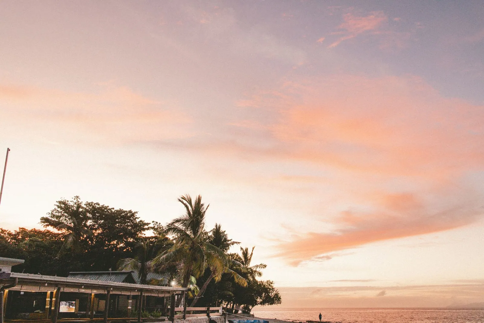 A tranquil sunset over a palm tree-lined beach in Nadi, Fiji