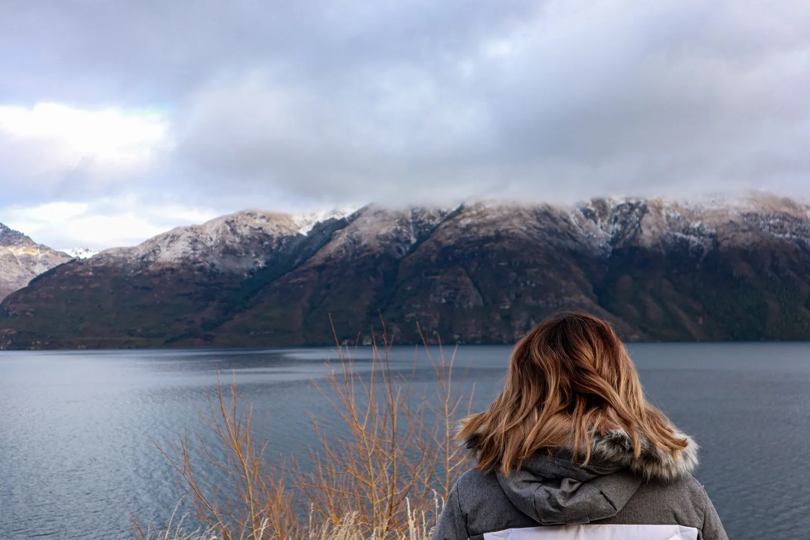 A woman gazing at Lake Wakatipu and snow-capped mountains in Queenstown, New Zealand