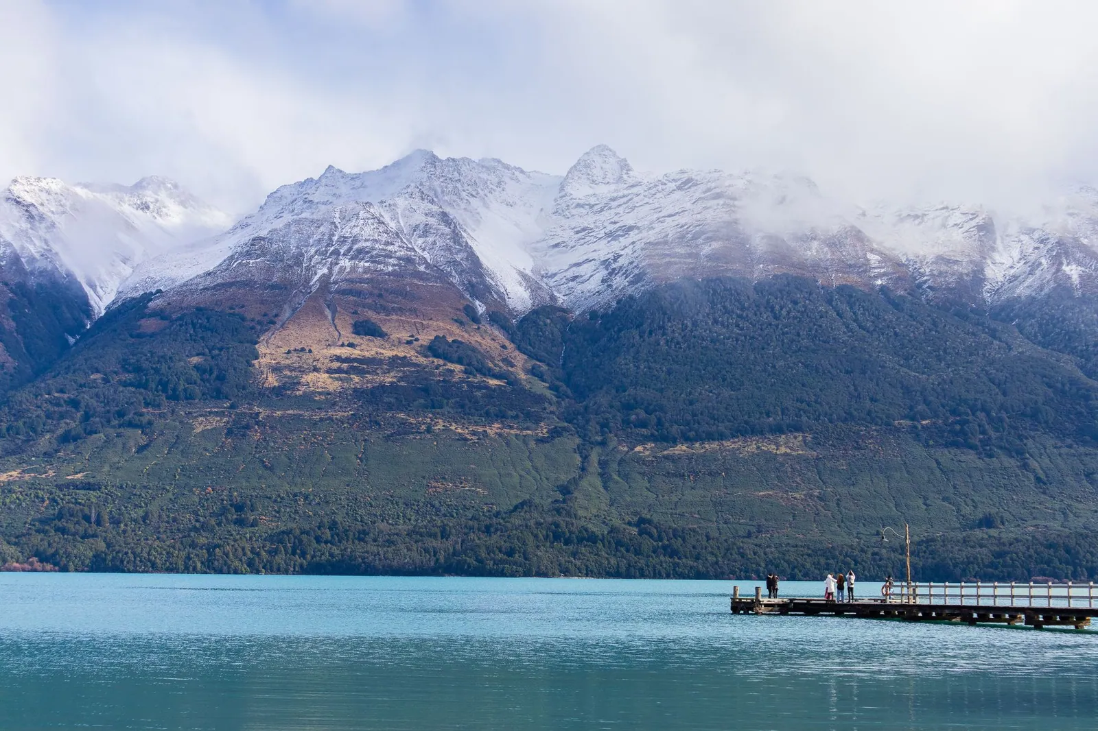 A dock on Lake Wakatipu with snow-capped mountains in Queenstown, New Zealand