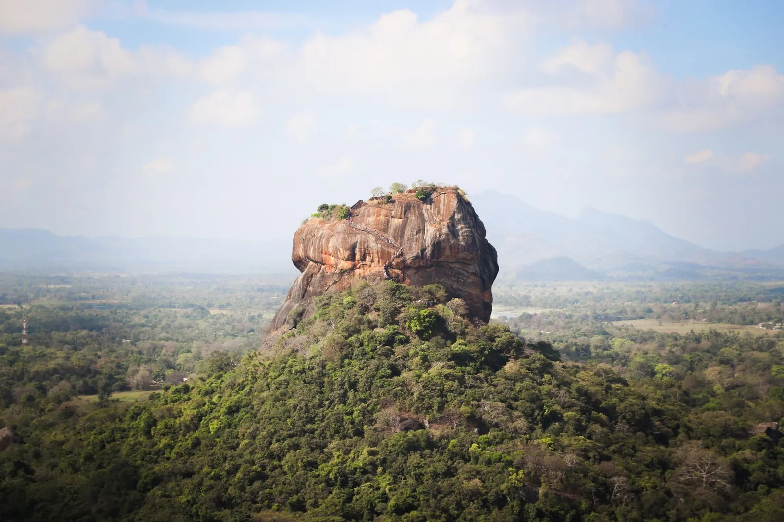 View of the iconic Sigiriya Rock Fortress, surrounded by lush vegetation in Sri Lanka