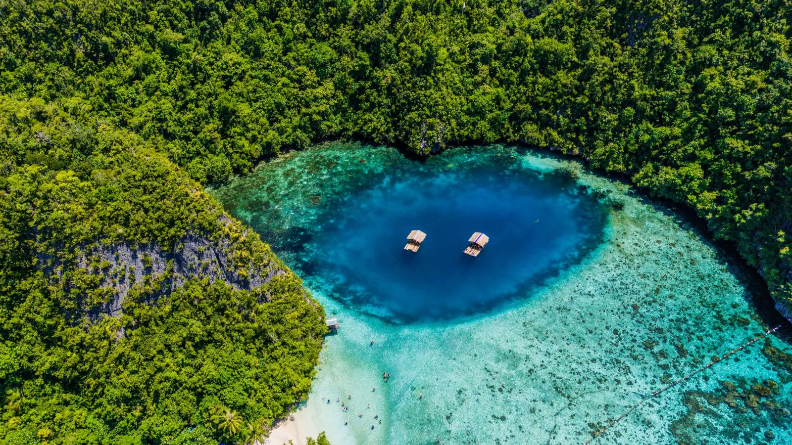An aerial shot of a blue lagoon surrounded by lush greenery in the Philippines