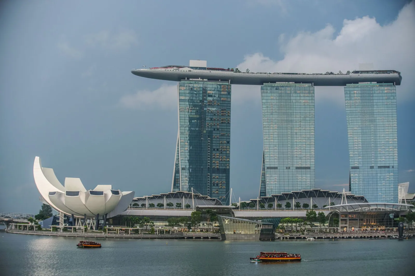 View of Marina Bay Sands and ArtScience Museum in Singapore's skyline with a boat on the bay.