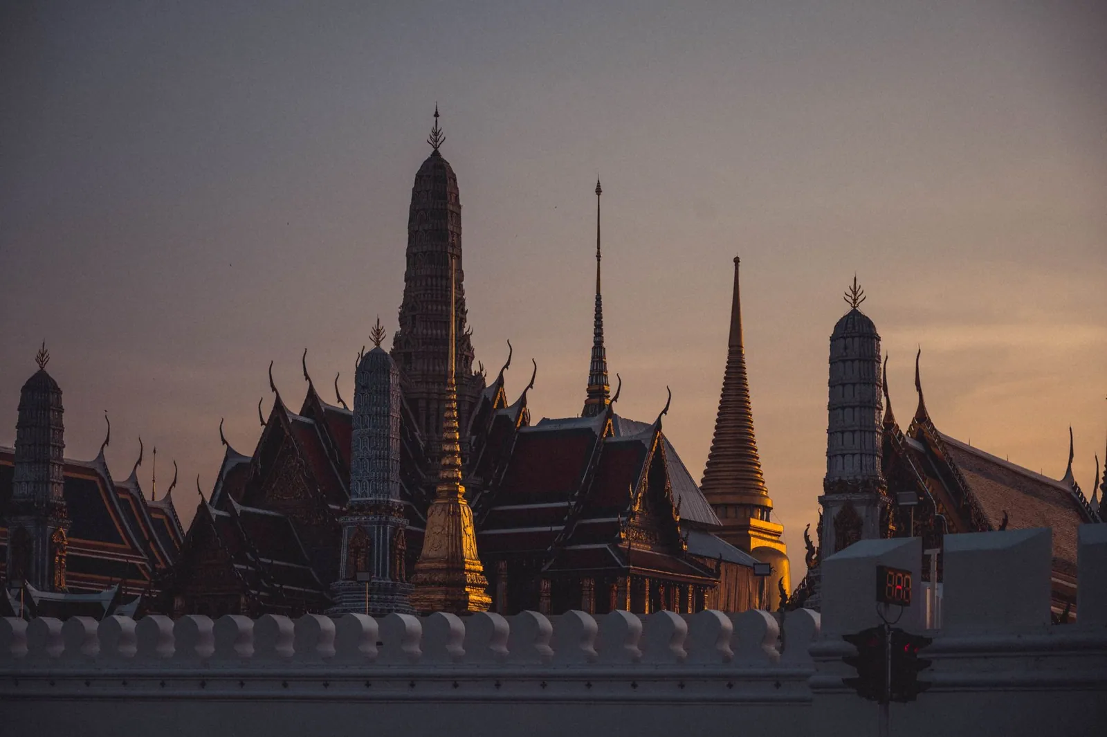 A dramatic sunset over Wat Phra Kaew, capturing the iconic temple spires in Bangkok, Thailand.
