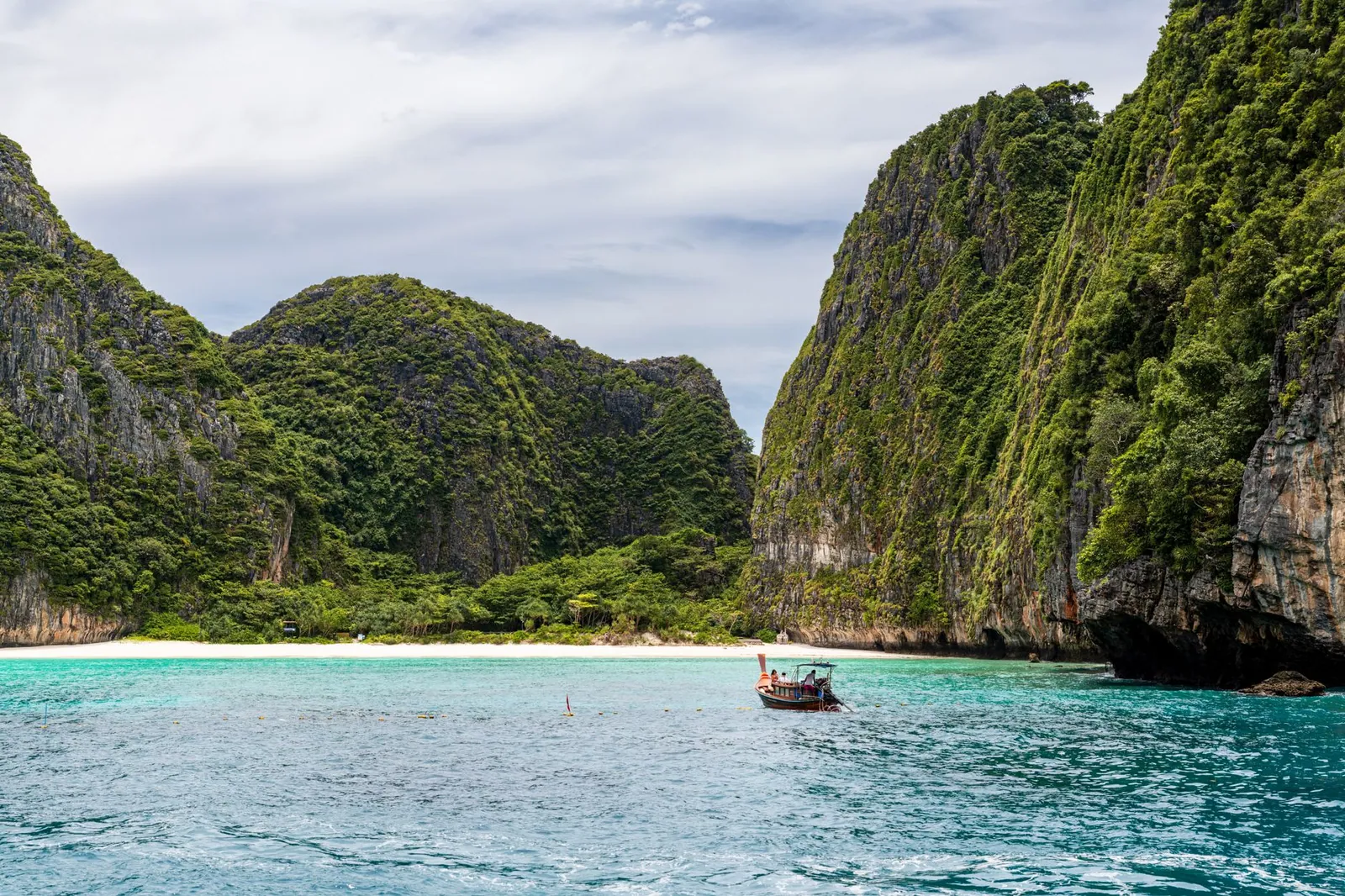 A traditional boat against limestone cliffs and turquoise waters in Phuket, Thailand