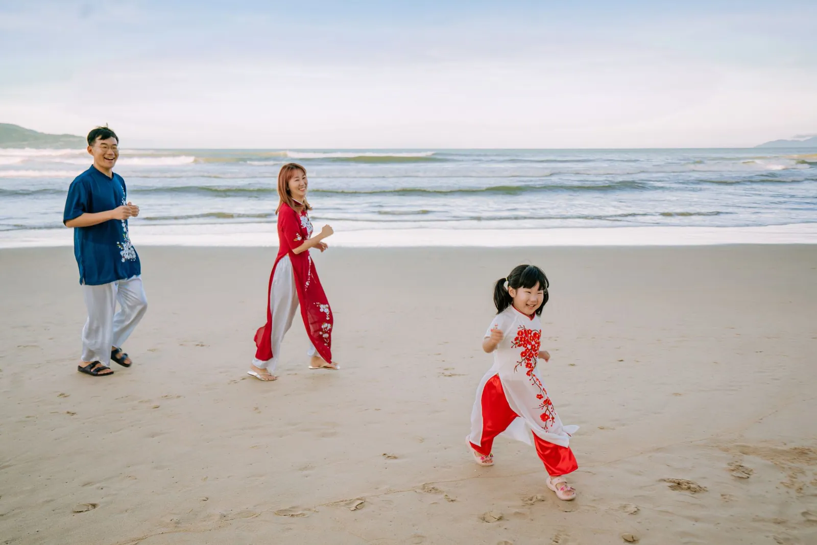 Family laughing and playing on a sandy beach on a bright sunny day