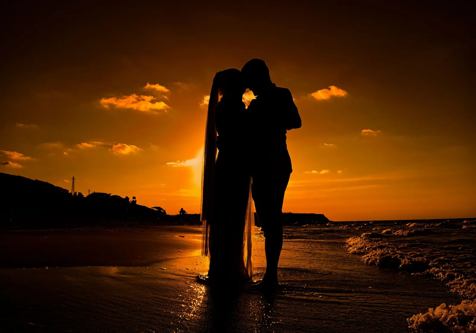 Silhouetted couple embracing on a beach at sunset, capturing romance and serenity.