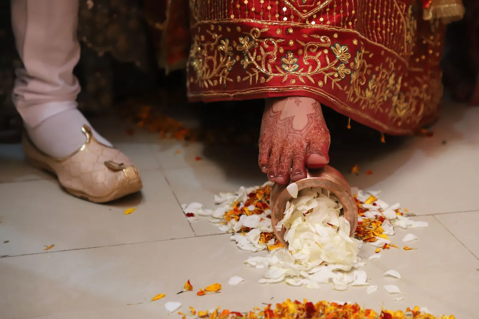 A bride performing a traditional Indian wedding ceremony ritual with flower petals