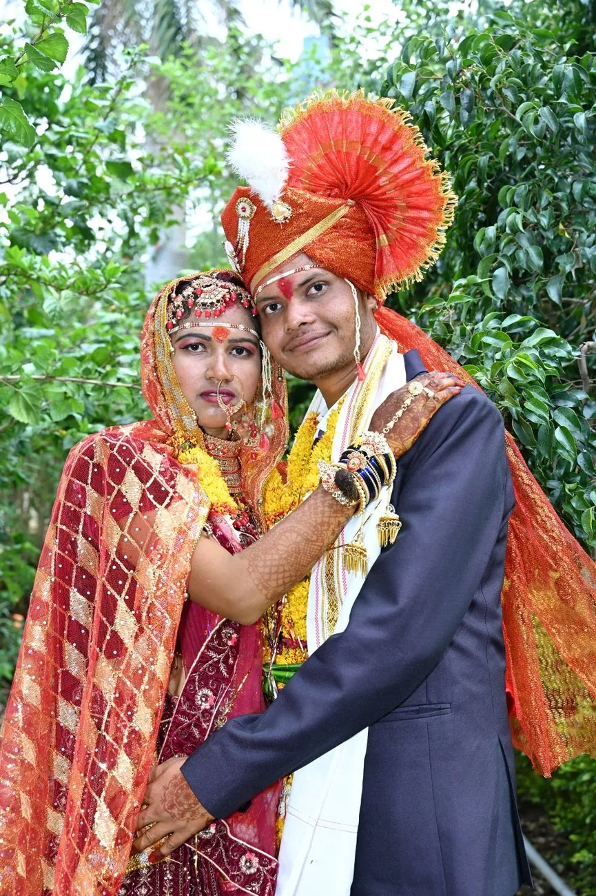 Indian couple in traditional attire posing during their wedding ceremony, embracing in an outdoor setting.
